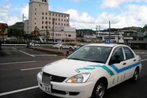 校舎を背に教習コースの車を撮りました。奥に見える建物は宿泊施設のホテル平成です。